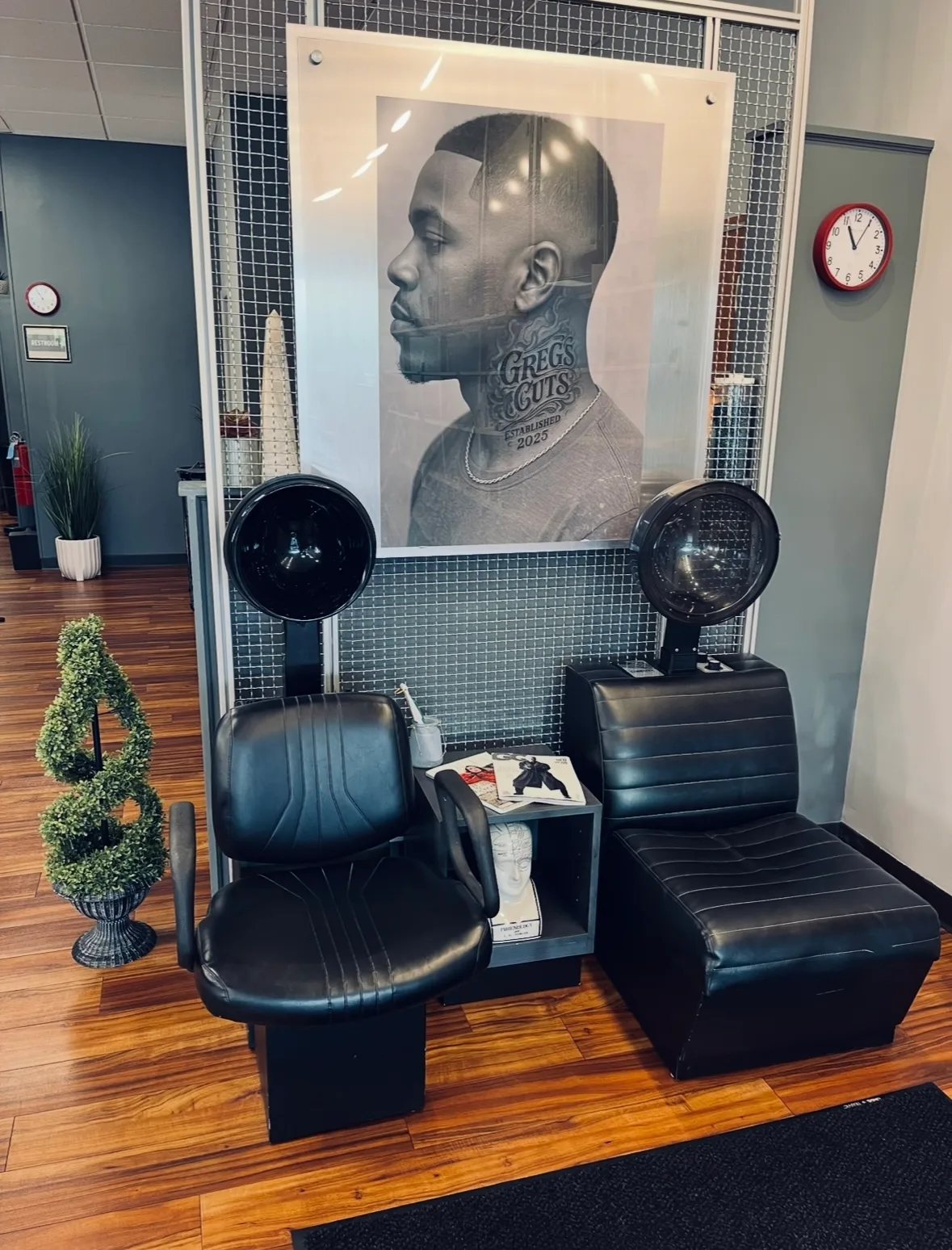 Hair dryer chairs beneath the Greg's Cuts portrait poster