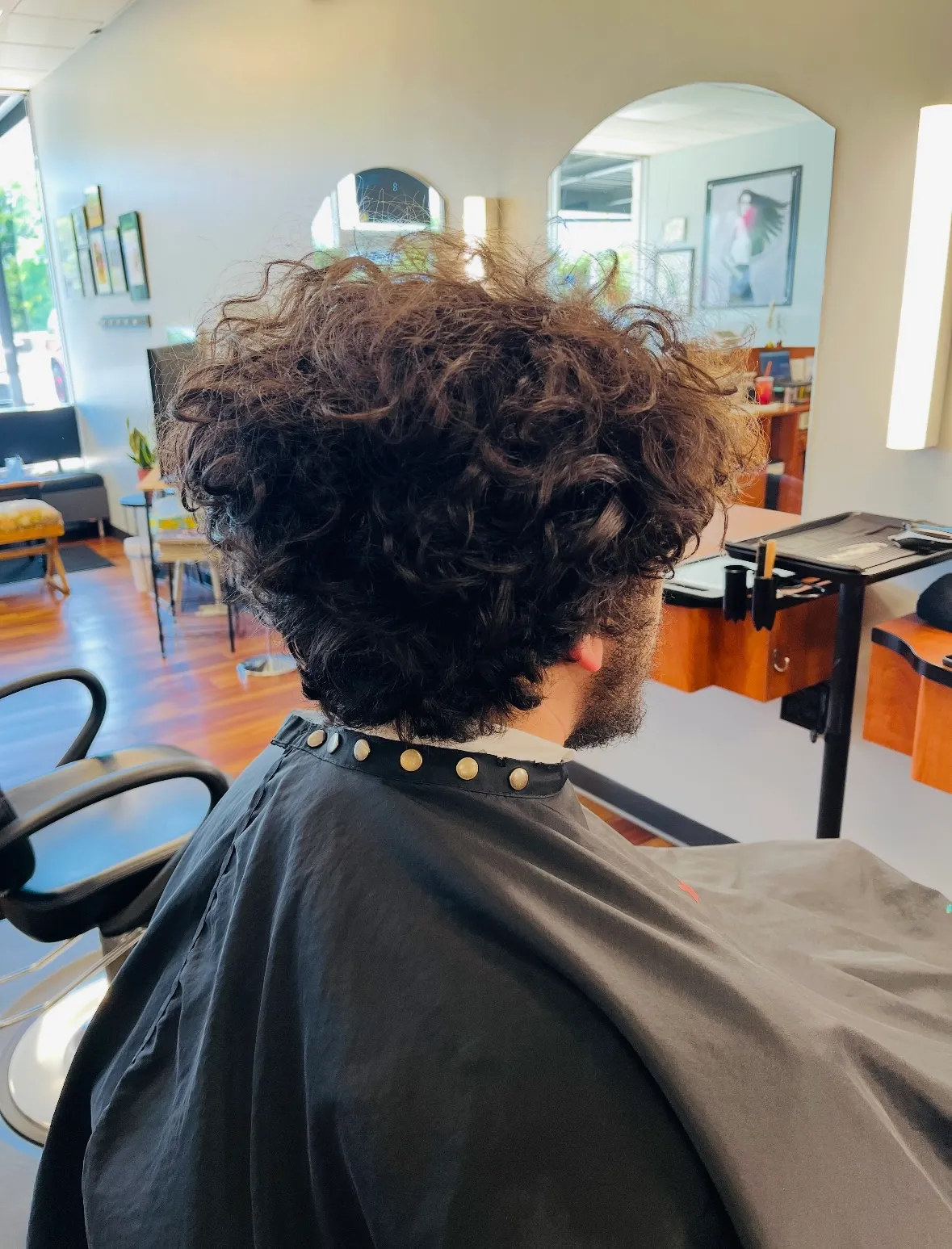 Before: a client's grown-out, curly hair seen from behind