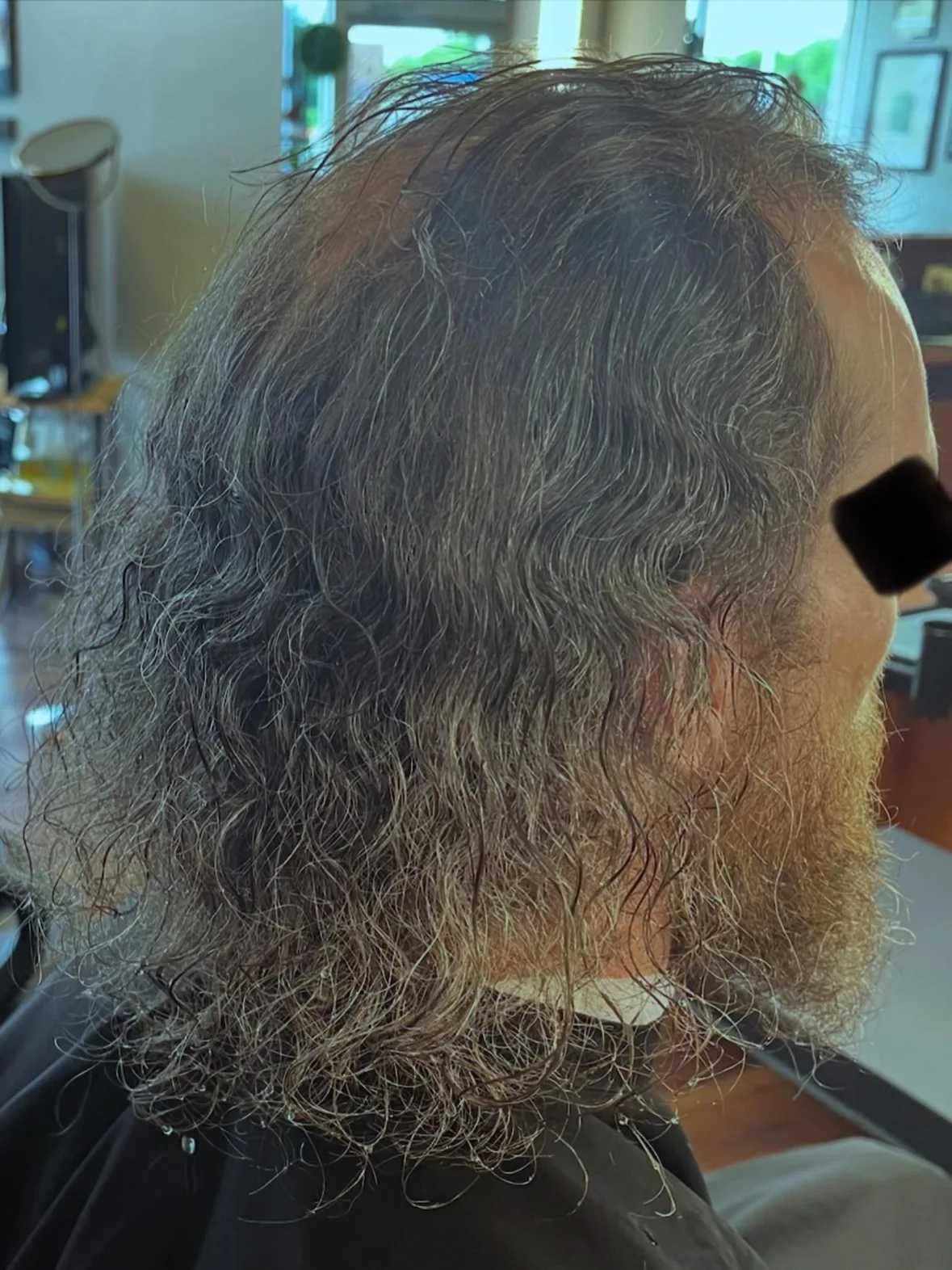 Before: long, frizzy hair grown well past the collar, seen from behind