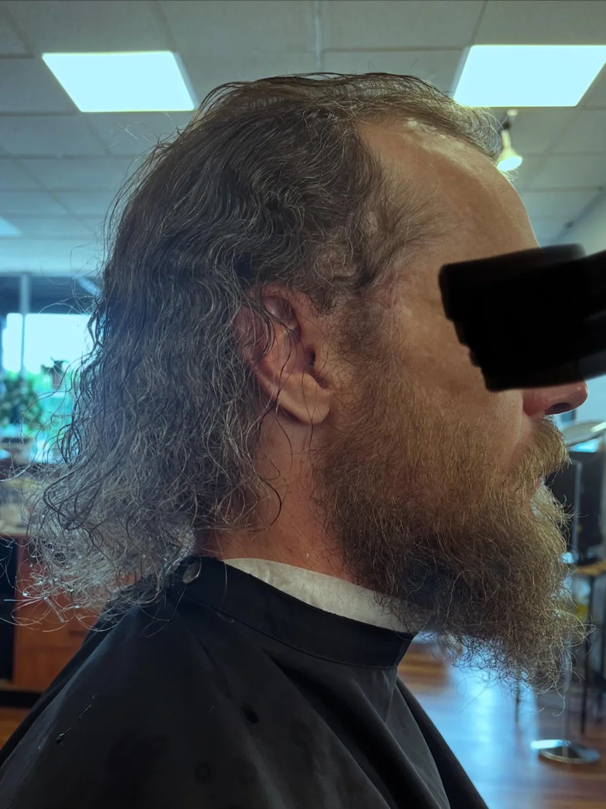 Before: long, wavy hair and a full, bushy beard in profile